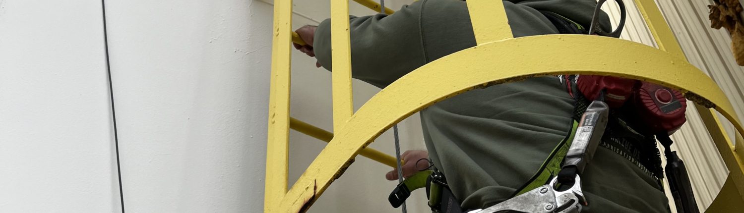 Matt Bonanni, Salesman of Harriman Material Handling, pictured climbing an outdoor ladder utilizing updated fall protection equipment required by OSHA.